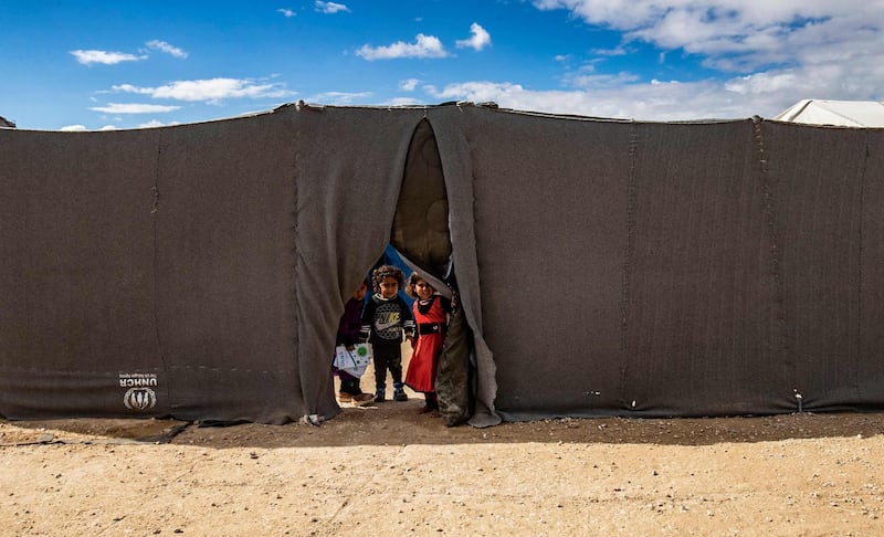 TOPSHOT - Children peek through the opening of a tent at the Kurdish-run al-Hol camp which holds suspected relatives of Islamic State (IS) group fighters, in the northeastern Syrian Hasakeh governorate, on February 17, 2021. / AFP / Delil SOULEIMAN
