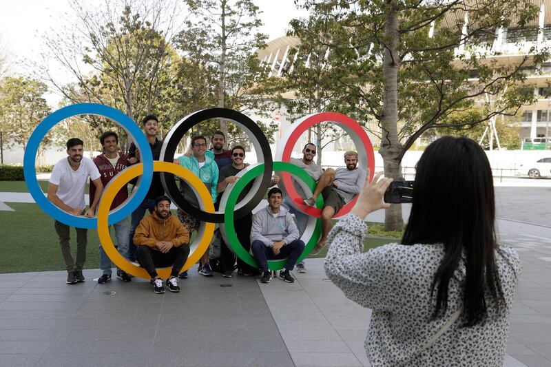 A group of students from Uruguay pose for a souvenir picture on the Olympic Rings set outside the Olympic Stadium in Tokyo on Saturday. AP