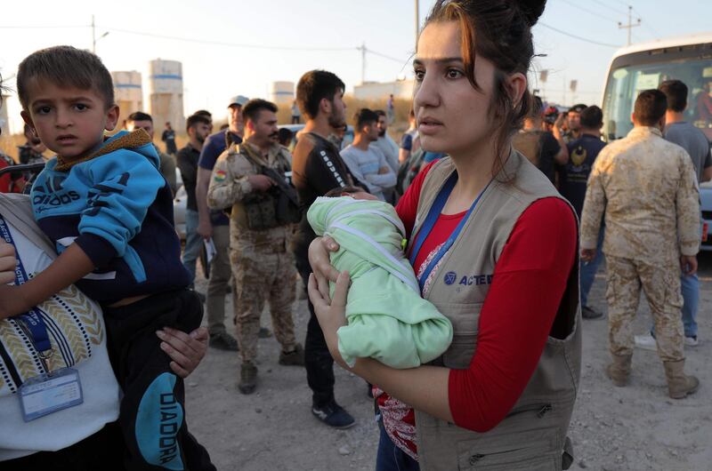 People holding children disembark from a minibus transporting Syrians who have been recently-turned refugees by the Turkish military operation in northeastern Syria upon arriving at the Bardarash camp, near the Kurdish city of Dohuk, in Iraq's autonomous Kurdish region, on October 16, 2019. Some 500 Syrian Kurds have entered neighbouring Iraqi Kurdistan over the past four days fleeing a Turkish invasion now entering its second week, officials said. Iraqi Kurdistan previously hosted more than one million Iraqis who fled fighting with the jihadists of the Islamic State group between 2014 and 2017.
 / AFP / Safin HAMED
