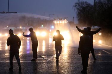 Youths gesture towards a police line blocking a road near the Peace Wall in West Belfast, Northern Ireland. AP