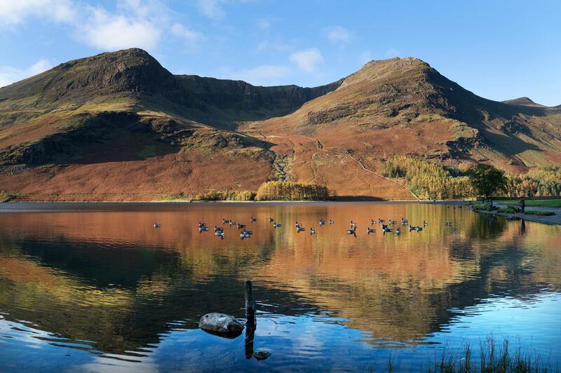 Photographers capture the autumn colours reflected in the water at Buttermere in the Lake District, Cumbria, northwest England. PA via AP