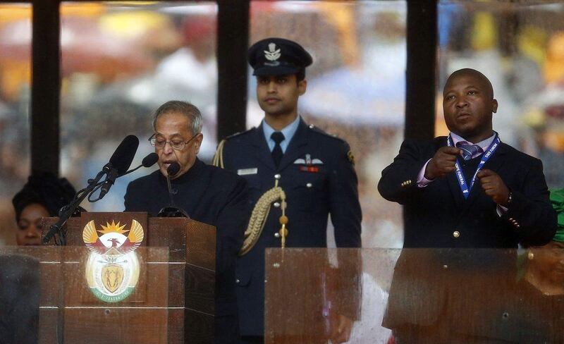 India's President Pranab Mukherjee speaks at the podium as Thamsanqa Jantjie, a sign language interpreter, beside him. Jantjie says he is a qualified interpreter but was 'hallucinating' on stage.   Kai Pfaffenbach / Reuters