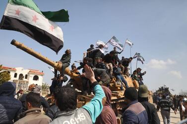 Syrians in protest climb atop a Turkish military M60T tank as they attempt to block traffic on the M4 highway, which links the northern Syrian provinces of Aleppo and Latakia, before incoming joint Turkish and Russian military patrols (as per an earlier agreed upon ceasefire deal) in the village of al-Nayrab, about 14 kilometres southeast of the city of Idlib and seven kilometres west of Saraqib in northwestern Syria on March 15, 2020. Russian President Vladimir Putin and his Turkish counterpart Recep Tayyip Erdogan reached a deal on March 5 to create a security corridor with joint Turkish and Russian patrols starting on March 15 along the key M4 highway in northern Syria, which runs roughly parallel to the border with Turkey, from northeastern Kurdish-controlled regions to the Mediterranean coast. / AFP / AAREF WATAD