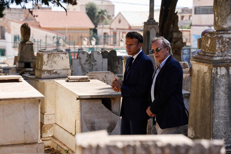 Mr Macron, left, and French film director Alexandre Arcady visit the Christian cemetery of Saint-Eugene in Algiers on August 26, 2022. AFP