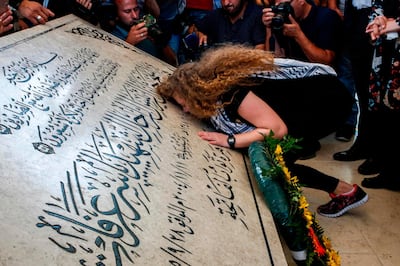 Palestinian activist and campaigner Ahed Tamimi kisses the tombstone of former Palestinian leader Yasser Arafat at his mausoleum in Ramallah in the occupied West Bank, on July 29, 2018, after she was released from prison earlier in the day following an eight-month sentence for slapping two Israeli soldiers.  / AFP / ABBAS MOMANI
