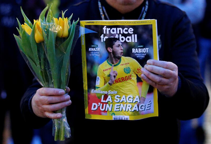 A man holds a sports magazine and yellow tulips as fans gather in Nantes' city center. Reuters