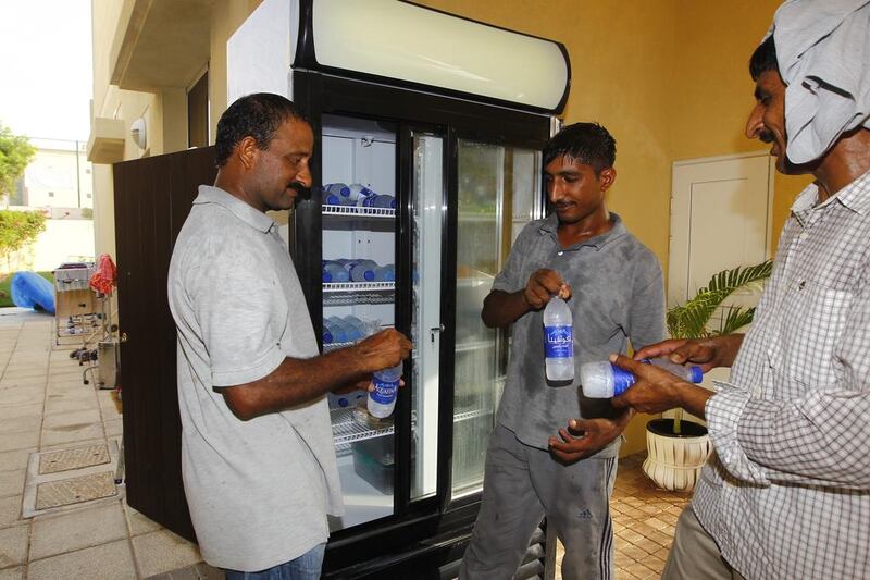 From left, Tariq Ajaib, Mohammed Israr and Chaudary Latif, all from Pakistan and working as gardeners, taking some water and food from a fridge in the garage of the Yel family villa. Jeffrey E Biteng / The National  