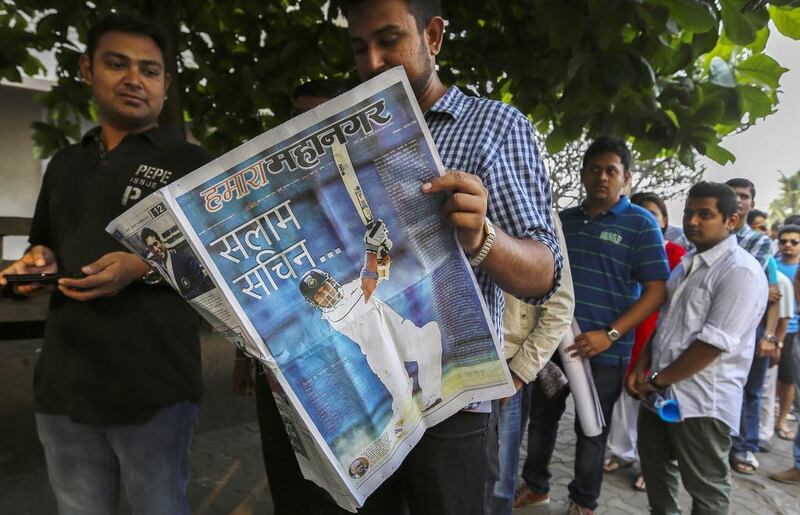 A fan queued up to get into the grounds reads a local paper on Thursday. Divyakant Solanki / EPA