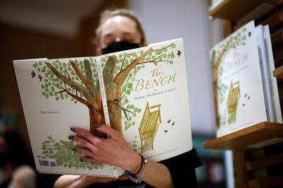 An employee poses with the children's book 'The Bench' by Meghan, Duchess of Sussex, which is inspired by her husband Harry and her son Archie, displayed in a bookshop in London on June 8, 2021, following its release.  / AFP / Tolga Akmen
