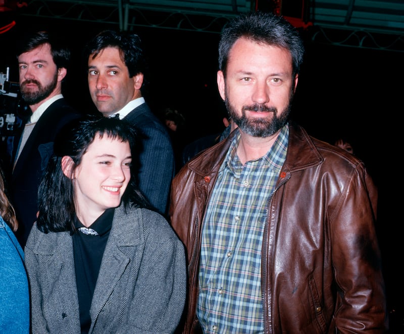 Winona Ryder, wearing a grey jacket over a black jumper and shirt, with Michael Nesmith of The Monkees at the premiere of 'Amazing Grace and Chuck' on March 26, 1987. Getty
