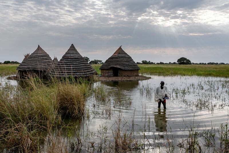 Yel Aguer Deng, who does not know his age, walks through water from his compound to the Wanyhok-Akon road, near Malualkon in Northern Bahr el Ghazal State, South Sudan, Wednesday, Oct.  20, 2021.  The worst flooding that parts of South Sudan have seen in 60 years now surrounds his home of mud and grass.  His field of sorghum, which fed his family, is under water.  Surrounding mud dykes have collapsed.  The United Nations says the flooding has affected almost a half-million people across South Sudan since May.  (AP Photo / Adrienne Surprenant)