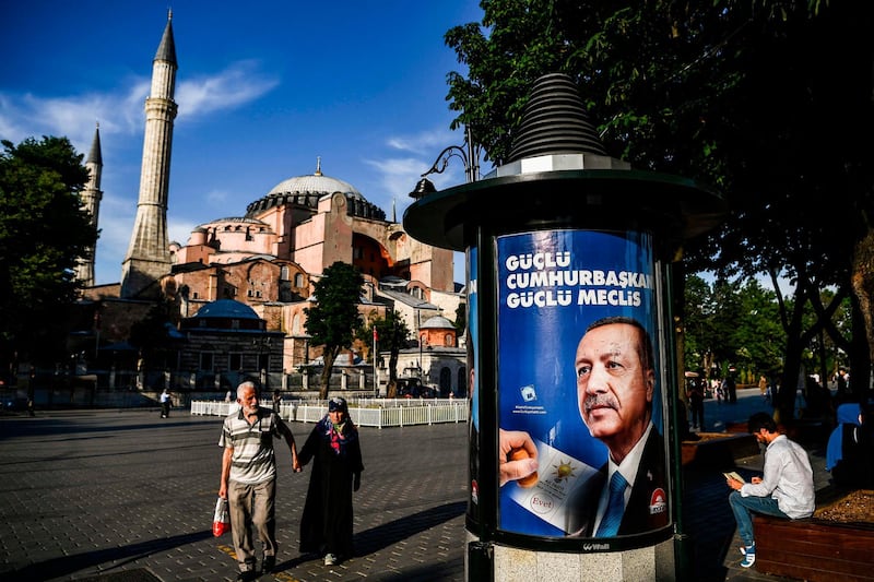 (FILES) In this file photo taken on June 19, 2018 people walk past a presidential campaign poster showing incumbent Turkish President Recep Tayyip Erdogan in front of Hagia Sofia museum in the historical district of Istanbul as Erdogan mooted on March 24, 2019 the possibility of renaming it as a mosque, in comments during a television interview.  / AFP / Aris MESSINIS

