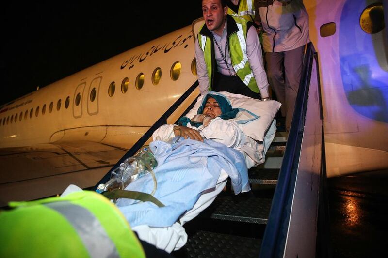 Paramedics carry a wounded Iranian woman from a plane after arriving in Tehran's Mehrabad airport, a day after she was injured in twin suicide bombings near the Iranian embassy in Beirut. Amir Kholousi / AFP



