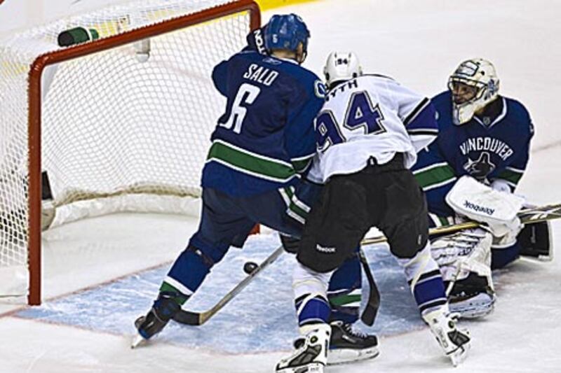 The Canucks goaltender Roberto Luongo, right, can only watch on as the LA Kings tie up the series with an overtime goal.