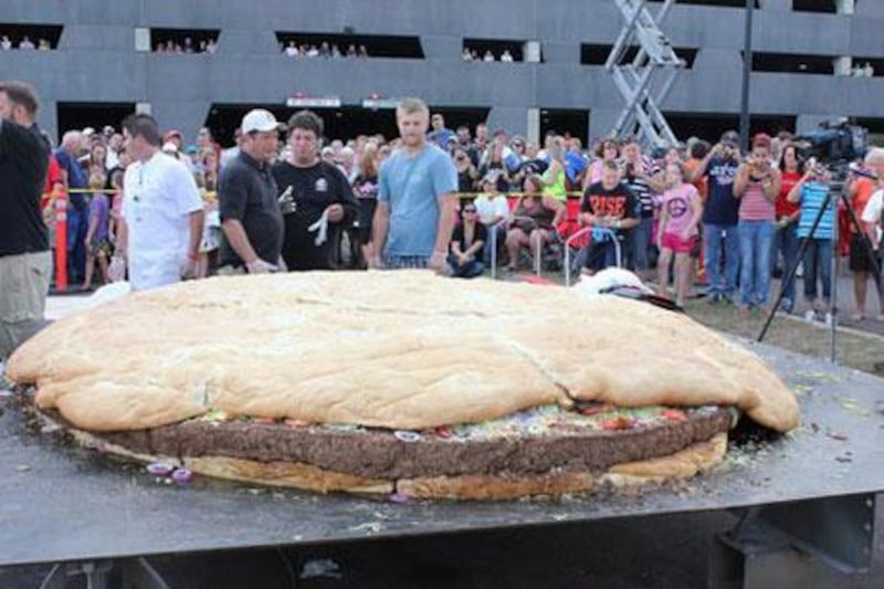 Men observe the behemoth burger in the United States which needed a crane to flip it while it cooked.