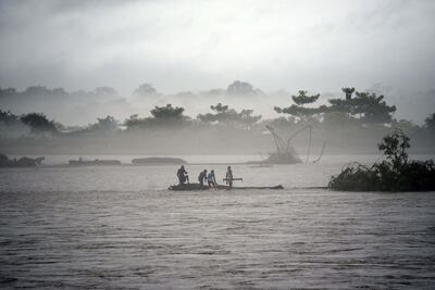 TOPSHOT - In this picture taken on July 15, 2019, Indian men catch a tree in the flooded Manas river, following heavy rainfall in Baksa district of Assam, in the North-Eastern states of India. Torrential monsoon rains swept away homes and triggered landslides across South Asia, affecting millions of people and spiking the death toll to at least 180, officials said on July 16.
 / AFP / David TALUKDAR
