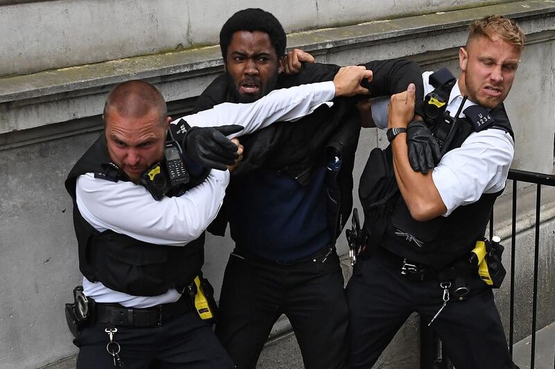 Police officers react as they attempt to detain a protestor near the entrance to Downing Street, during an anti-racism demonstration in London.  AFP