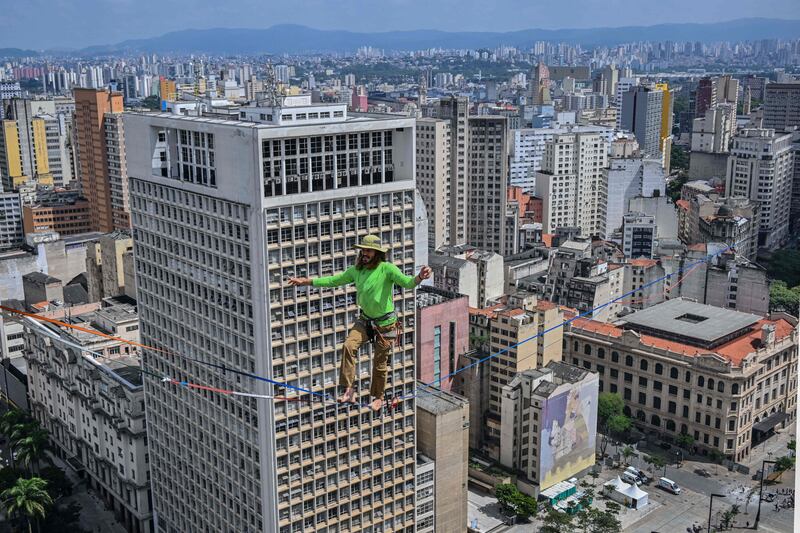 Brazilian highliner Rafael Bridi performs on a slackline 114 meters high and 510 meters long, crossing the entire Vale do Anhangabau, as part of the 469th anniversary of the city of Sao Paulo, Brazil on January 25, 2023.  - Bridi broke his own urban distance record for the Americas, according to the International Slackline Association.  (Photo by NELSON ALMEIDA  /  AFP)