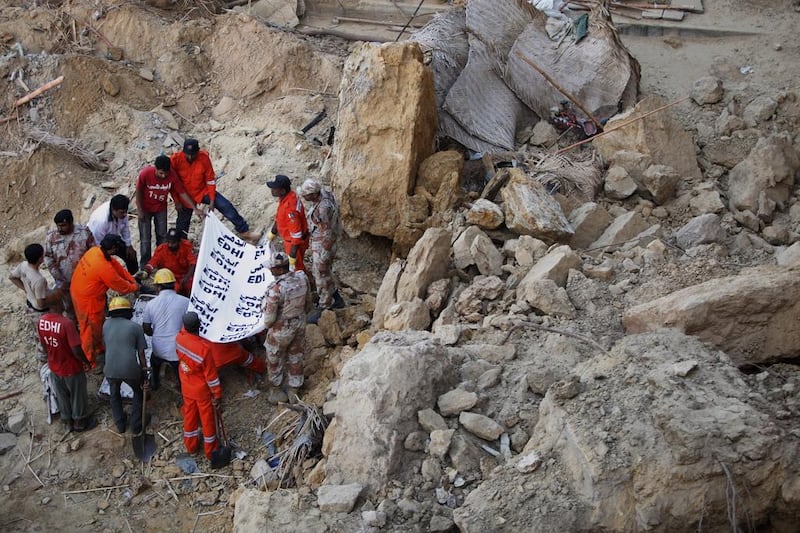Pakistani rescue workers remove a dead body from the site of landslide in Karachi. Shakil Adil / AP