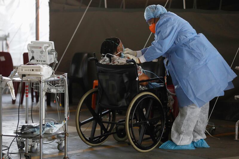 A healthcare worker wearing personal protective equipment (PPE) stands next to a patient at the temporary wards dedicated to the treatment of possible COVID-19 coronavirus patients at Steve Biko Academic Hospital in Pretoria, South Africa.  EPA