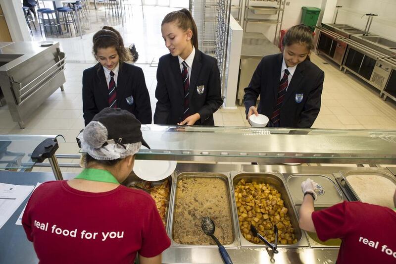 Pupils at Brighton College, Al Ain, from left to right, Dara Hussein, Zoe Claudel and Aliya Davletova wait in line to have their lunch served at the Slices cafeteria. Antonie Robertson / The National 