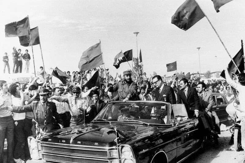 Fidel Castro rides with Chilean president Salvador Allende through a crowd waving communist flags in Santiago, Chile, on November 10, 1971. AP Photo