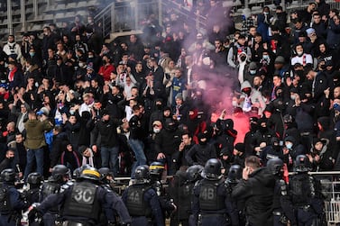 (FILES) In this file photo taken on December 17, 2021 French anti-riot police officers arrive as supporters light a flare at half-time during the French Cup round of 64 football match between Paris FC and Olympique Lyonnais (OL) at the Charlety stadium in Paris.  - Ten days after the incidents in the stands during the Coupe de France match between Paris FC and Lyon, the Disciplinary Commission of the French Football Federation (FFF) will hear the various parties on December 27, 2021,  before rendering its decisions the same day.  (Photo by BERTRAND GUAY  /  AFP)