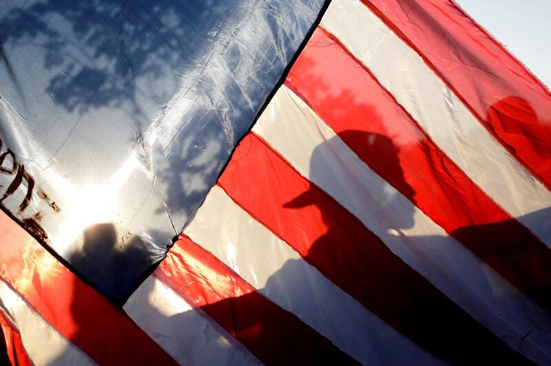 The shadow of a migrant is seen on a flag as he walks on a road, in the outskirts of Ciudad Hidalgo, Mexico. Reuters