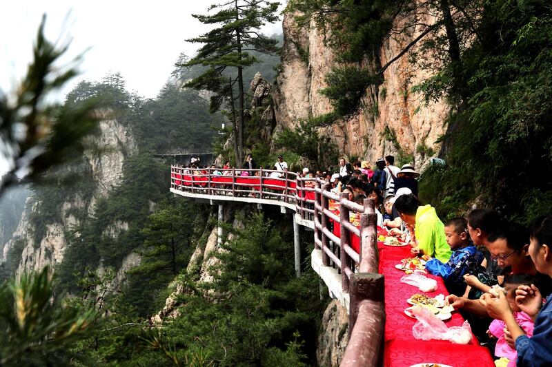 Tourists during a banquet held along the edge of a cliff, at Laojun Mountain in Luoyang in China's central Henan province. The banquet was held on a 2,000-metre (6,500-ft.) high cliff. AFP