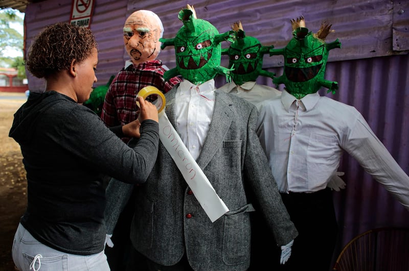 A woman tapes the word "Omicron" to a handmade effigy depicting the Omicron coronavirus variant in Managua. The effigies will be burnt at midnight on December 31 as a tradition of saying goodbye to the old year and welcoming the new.  AFP
