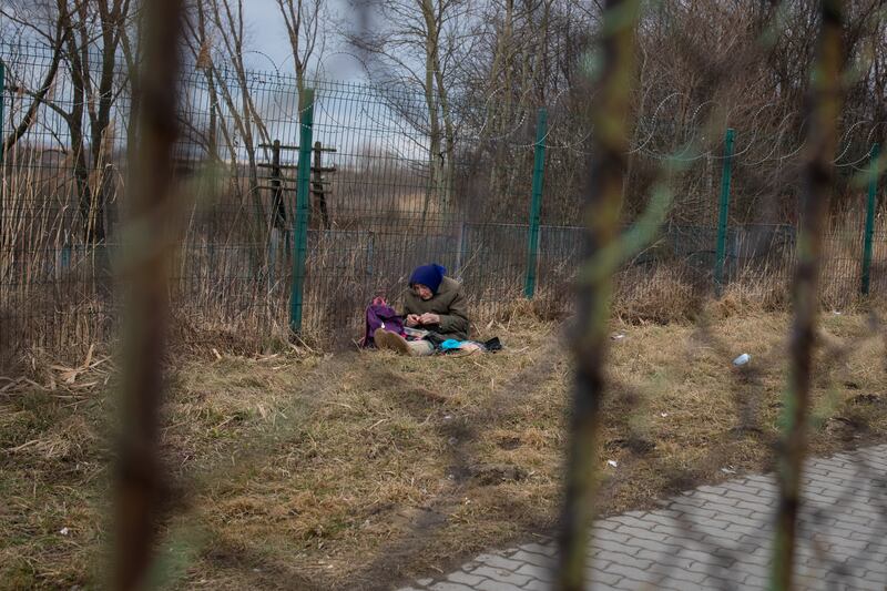 An elderly woman sits alone waiting to cross the border from Ukraine into Poland as fighting continues.