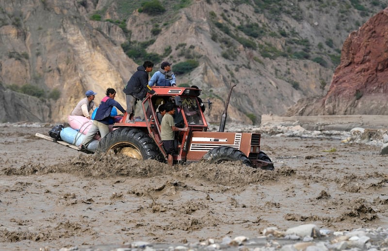 A tractor transporting farmers' produce to sell at the markets, crosses the La Paz river inundated by a mudslide in El Penol, Bolivia. AP 