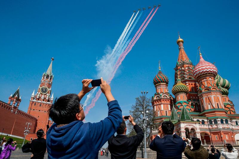 Tourists take pictures with their mobile phones as Russian Su-25 aircraft fly over tthe Red Square in Moscow. Maxim Zmeyev / AFP