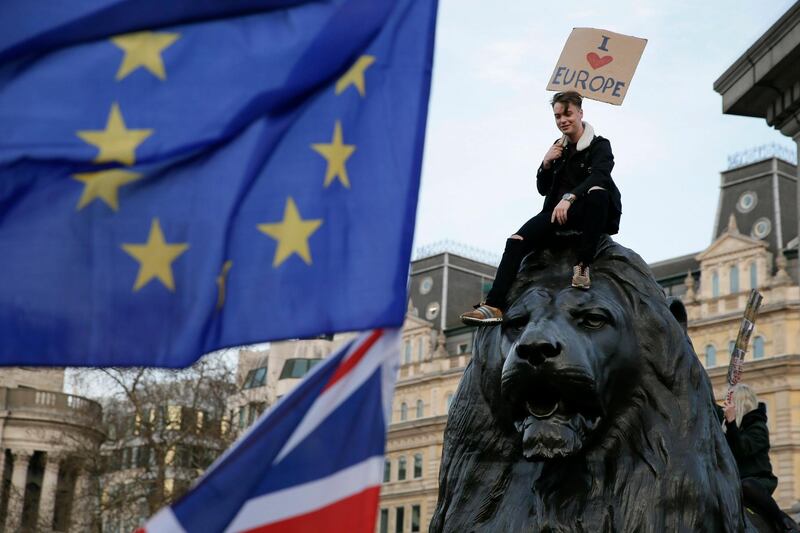 A demonstrator sits on one of the lions in Trafalgar Square. AP Photo/Tim Ireland