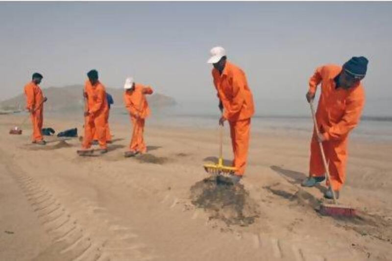 Workers from the Sharjah Municipality clean up a beach after an oil spill off the coast of Fujairah at Khor Fakkan in 2008. Randi Sokoloff / The National