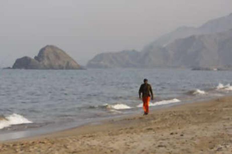 A man walks on Al Aqah beach near Le Meridian hotel in Fujairah. The north-east coast has been hit by oil spills and red tide.