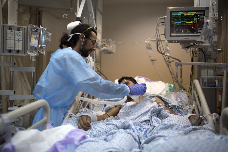 An Israeli medical staff member tends to a Syrian young boy, who was wounded in the violence in Syria, as he lies on a hospital bed during his treatment at Ziv hospital, which perches on a rocky hilltop in the upper Galilee town of Safed.  Menahem Kahana / AFP