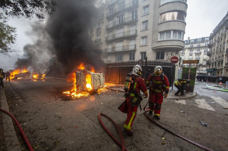 Firefighters work to put out cars set on fire on a road near the Arc de Triomphe in Paris. Getty Images