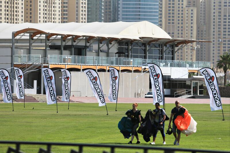 Dubai, September 2, 2013 - A trio walks with their deployed parachutes in front of Zero Gravity, a new restaurant and bar part of the Skydive Dubai Drop Zone at Skydive Dubai, September 2, 2013. (Photo by: Sarah Dea/The National, Story by: Melanie Swan) *** Local Caption ***  SDEA010913-skydivedubai03.JPG