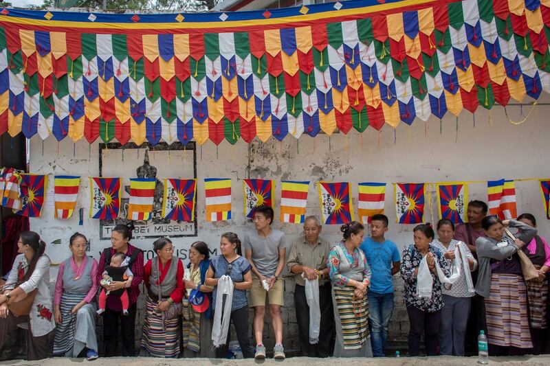 Exile Tibetans wait with ceremonial scarves to welcome their spiritual leader the Dalai Lama who returned home after a speaking tour in Europe, in Dharmsala, India. Ashwini Bhatia / AP Photo