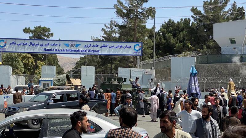 Members of the Taliban stand guard outside the Hamid Karzai International Airport as people  try to flee the country.