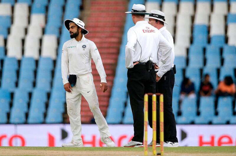 Indian Captain Virat Kohli (L) reacts as umpires suspend play due to bad light during the third day of the second Test cricket match between South Africa and India at Supersport cricket ground on January 15, 2018 in Centurion, South Africa.   / AFP PHOTO / GIANLUIGI GUERCIA