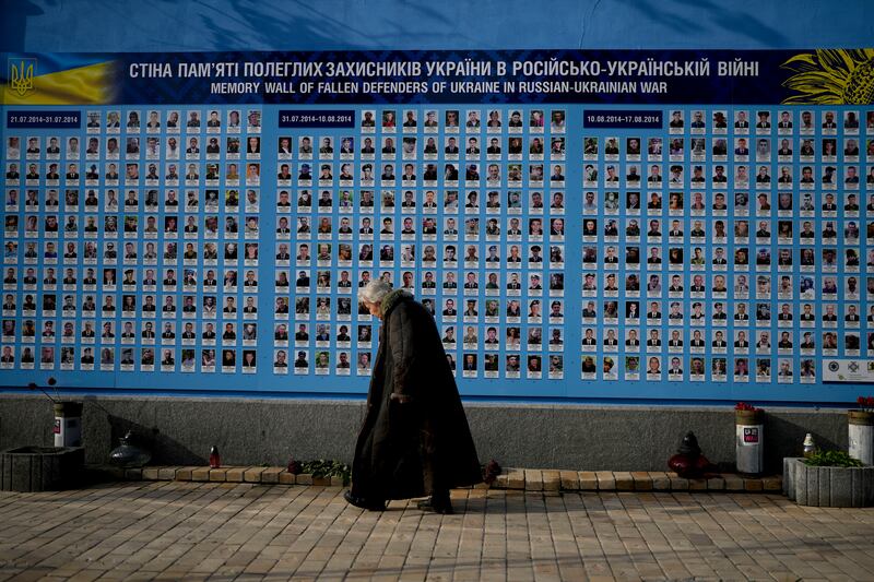 A woman walks past a memorial wall for Ukrainian soldiers in Kyiv. AP