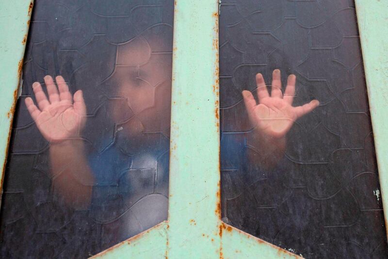 An Iraqi child looks out through a window pane amid confinement due to the pandemic, in the southern city of Basra.  AFP