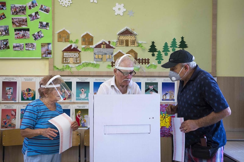 People wearing face cover cast their vote at a polling station during the general election in Skopje. North Macedonia went to the polls on July 15, 2020 to elect a new parliament.  AFP