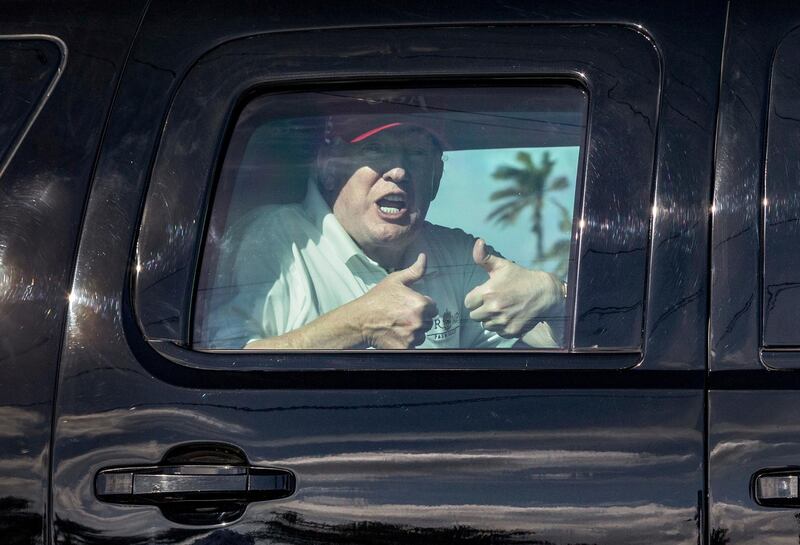 President Donald Trump gives two thumbs up to cheering supporters from his motorcade heading to his Mar-a-Lago estate after spending the morning at Trump International Golf Club, Friday, Dec. 29, 2017, in West Palm Beach, Fla. (Greg Lovett / Palm Beach Post via AP)
