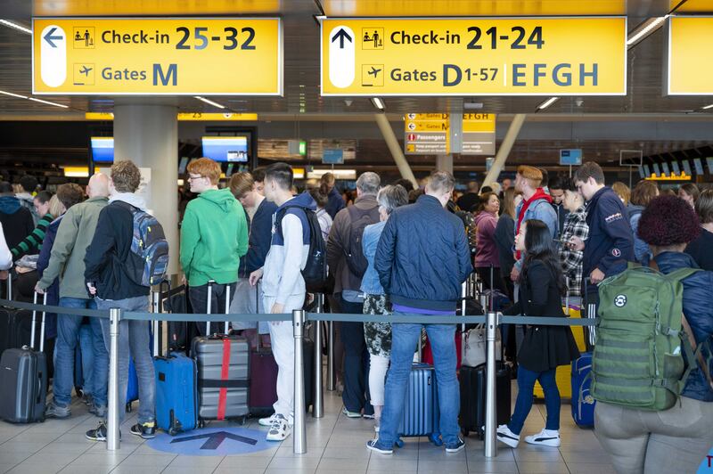 Travellers wait at Schiphol airport. EPA