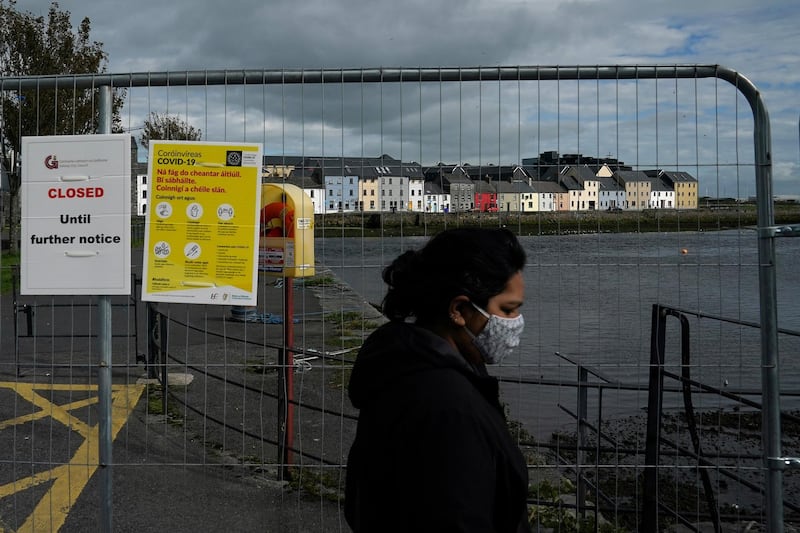 A woman wearing a protective face mask walks past a closed main walkway as the National Public Health Emergency Team (NPHET) announces recommendations that the government implement the highest level of Covid-19 restrictions in Galway, Ireland. Reuters