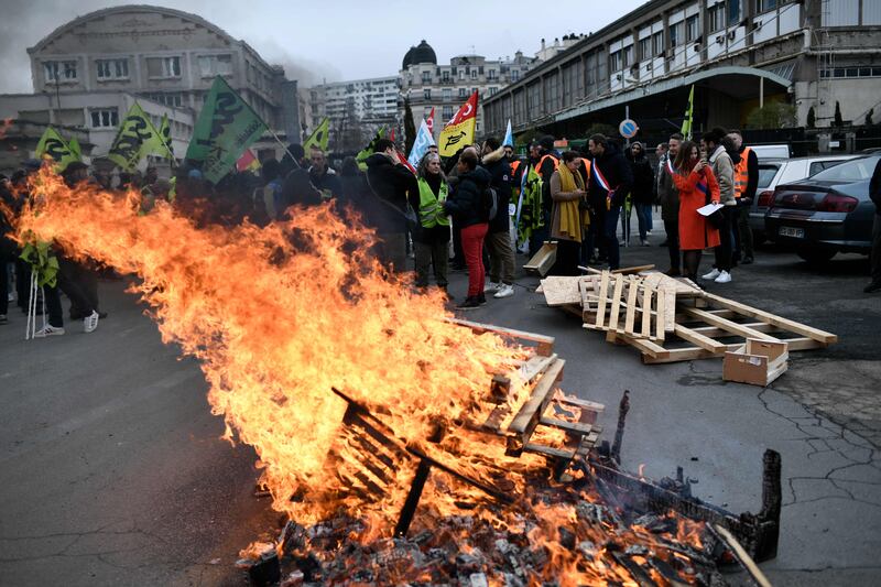 Wooden pallets burn, as demonstrators gather during a rally called by French trade unions in outside the Gare de Lyon, in Paris on January 19, 2023.  - A day of strikes and protests kicked off in France on January 19, 2023 set to disrupt transport and schooling across the country in a trial for the government as workers oppose a deeply unpopular pensions overhaul.  (Photo by STEPHANE DE SAKUTIN  /  AFP)