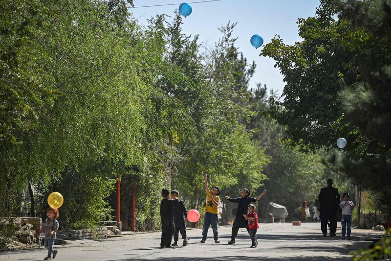 Children play with balloons on a street in Kabul. AFP